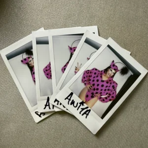 A stack of Anita Piss BBC Socials polaroids, each signed by hand in black marker
